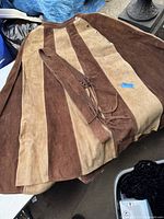 Photo showing full skirt laid flat highlighting the alternating brown and tan suede panels and matching suede belt with tassels.