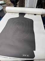 Rolled large police silhouette target with black figure and white rings on paper.
