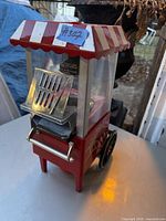 Front view of Betty Crocker popcorn maker showing red and white canopy roof, ventilation slots, and part of the electric cord.