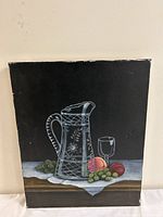 Front view of the still life painting depicting glass pitcher, wine glass, grapes, and peaches on cloth.