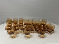 Full view of 20 amber stem glasses on a white background, arranged in two rows by style.