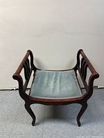 Front view of the antique throne style chair showing the seat and wooden frame with curved armrests and legs.