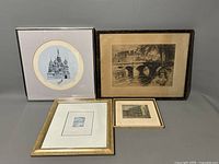 Four framed art pieces arranged on a flat surface including round and rectangular lithographs/etchings showing architectural and bridge scenes.
