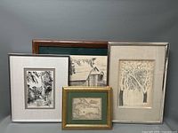 Full view of the five framed lithographs arranged side by side. Visible details include framing materials, black and white drawings, and map with gold frame.