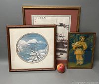 Three framed Asian lithographs of varied size with stands visible, showcasing traditional themes and signatures. The lot includes a large horizontal frame, a smaller vertical frame with figure, and a circular snowy landscape print.