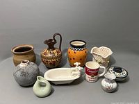 Full overview photo showing all nine ceramic and pottery items arranged together on a grey surface.