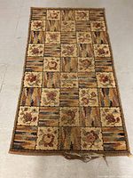 Full view of hand woven rectangular rug showing patchwork floral and striped block design in earth tones