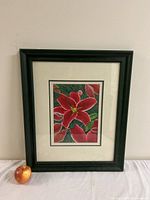 Framed floral watercolor painting with red flowers and green leaves, with apple beside for scale.