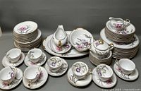 Full display of the Grace China Charleston pattern dinnerware showing multiple stacked plates, bowls, cups and saucers, and serving pieces with floral and gold trim design.