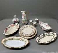 Photo showing the entire porcelain collection including plates, trays, vase, pitcher, and cups arranged on a gray background.