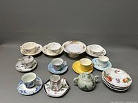 Full lot overview showing various porcelain cups, saucers, bowls, a comport, and a sugar bowl arranged in rows.