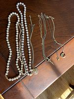 Overview of pearl and chain necklaces laid on a wood surface.