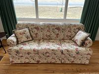 Full front view of floral pattern couch with two matching pillows placed on either armrest