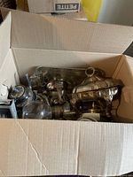 Box with various silverware items including trays, teapots, and serving pieces