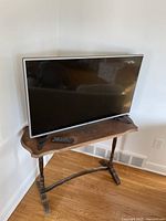 Full view of the LG 42-inch LED TV on a decorative wooden table, with the remote control placed in front.
