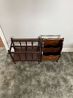 Two wooden magazine racks side by side on carpet, one with vertical slats and one with tiered carved design
