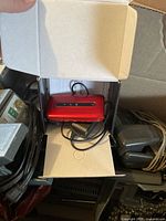 Red new old stock cell phone in box with attached charger cable.