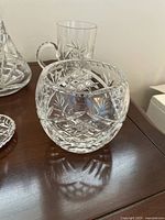 Spherical bowl with detailed cut crystal patterns showing diamond and starburst motifs on wood surface.