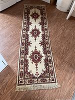 Full view of the decorative 8x27 rug runner laid flat on wood floor, showing the detailed traditional medallion and border patterns with fringed ends.