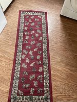 Full view of the rectangular red floral pattern rug runner on wooden floor, showing the entire length of the rug.