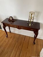 Front view of the wooden side table hutch showing three drawers and decorative items on top.