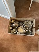 Top view showing boxed assorted silverware items including trays, bowl, candle holders and trivet with tarnishing visible