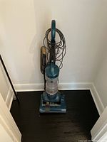 Full front view of the blue Kenmore upright vacuum cleaner showing dust container, hose, and power cord wrapped on handle.