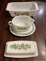Photo showing a rectangular baking dish, a gravy boat with blue matching underplate, and a butter dish with lid. All have the green floral Spring Blossom Pyrex pattern.
