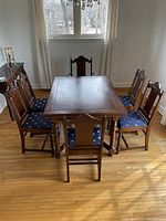 Dining table with six blue upholstered chairs around it, showing the set as a whole