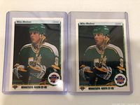 Front of two Mike Modano rookie cards in clear protective cases showing the player in green Minnesota North Stars uniform.