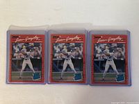 Front side of three 1990 Juan Gonzalez rookie baseball cards in protective plastic cases, showing player batting in Texas Rangers uniform with number 18.