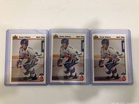 Front view of three Teemu Selanne hockey cards in protective plastic cases, each featuring Selanne in white hockey uniform in skating pose.