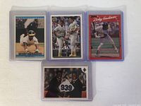 Front of four Rickey Henderson baseball cards in protective plastic sleeves showing various images of Henderson.
