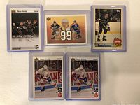 Front side of 5 Wayne Gretzky hockey cards in protective sleeves showing Gretzky in various team uniforms and a number 99 design