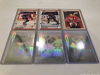 Six hockey cards arranged in two rows, top row shows Mark Messier, Craig Muni, Eric Staal cards, bottom row shows three holographic cards with reflective, shiny surfaces.