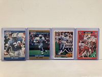 Front view of four Barry Sanders football cards in protective cases with different designs and colors visible.