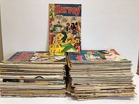 Two stacks of mixed Archie and related comics with a Harvey comic on display behind.