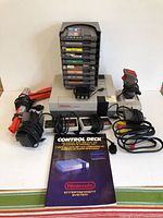 Overview: NES console, controllers, turbo joystick, Zapper light gun, adapters, manual, stacked game cartridges