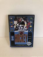 Front cover of Sega Genesis NHL Hockey video game case showing hockey players in action and the game title.