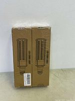 Two sealed LED corn light bulbs in brown cardboard boxes with the product image and label visible.