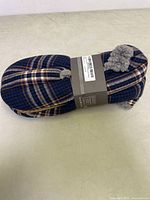 Pair of men's navy plaid slippers, side view showing plaid pattern and gray plush lining