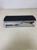 Side view of Ernie Ball VP JR volume foot pedal with black textured pedal surface on silver base.