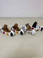 Front side view of four wooden Hudson Bay canoe animal ornaments, aligned side by side showing painted detailing and carved animals.