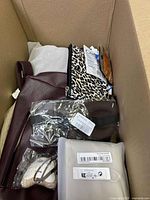 Photo of large maroon handbag with leopard print pouch and other small packaged items inside a box.