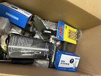 Top-down photo showing the box with multiple packaged and loose items including rotary carver box, blue boxed components, and a pack of ARP brass adapters.