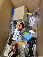 Top view of the large box showing a variety of tools, electrical components, cables, and hardware items packed loosely inside.