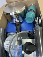 Box containing various kitchen and household items, top view showing pot, water bottle, hooks, and other items