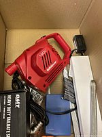 Large misc box with red 120V Quick Pump tool, blue battery or power pack, black power adapter, and OMT Heavy Duty Tailgate Shock box inside.