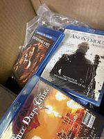 Photo showing three DVD or Blu-ray cases featuring the titles 'Catching Fire', 'Anonymous', and 'Three Days Grace'.