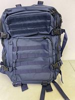 Front view of the navy blue tactical backpack showing two large compartments with MOLLE webbing and compression straps.